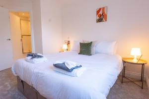 une chambre avec un grand lit blanc avec des serviettes dessus dans l'établissement Kingston Centre Location 2 Bed Apartment, à Kingston upon Thames