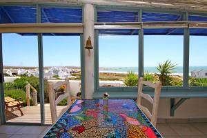 a table and chairs on a porch with a view of the ocean at Gilcrest Place Guest House in Paternoster