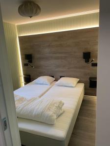a bed with white sheets and pillows in a room at Hornsjöns Pensionat in Löttorp