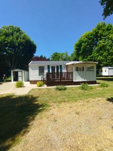 a small house with a porch and a deck at Mobil home Le Duo Tranquille in Souvigné