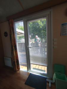a man standing on a balcony outside a sliding glass door at Mobil home Le Duo Tranquille in Souvigné +28 photos