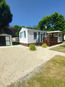 a small white house with a porch and a deck at Mobil home Le Duo Tranquille in Souvigné