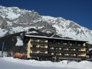 a building in front of a snow covered mountain at Ferienhotel Knollhof in Ramsau am Dachstein