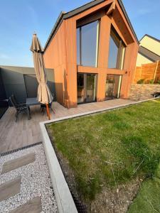 a house with an umbrella and a patio with a lawn at Le gîte du Mawet in Léglise