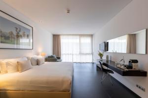 a white bedroom with a large bed and a desk at Troia Design Hotel in Troia