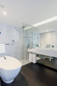 a bathroom with a tub and a sink and a toilet at Troia Design Hotel in Troia