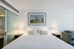 a bedroom with a large white bed and a chair at Troia Design Hotel in Troia