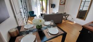 un tavolo da pranzo con piatti bianchi e fiori sopra di La Parenthèse, Rez de jardin indépendant, 4 étoiles a Fleurieu-sur-Saône