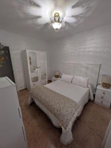a white bedroom with a bed and a chandelier at El HORTAL in Alberite +3 photos