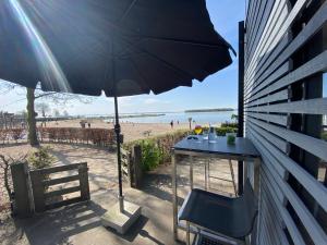 stół z parasolem przy plaży w obiekcie BEACH VILLA in erster Reihe - direkter Strandzugang - eingezäunter Garten - Dachterrasse - 2 Gartenterrassen - Terrassendach - Grill mit Plancha - XXL Meerblick - Bar - SONOS Soundanlage - Pool Whirlpool - kinderfreundlich - Hunde willkommen w mieście Hulshorst