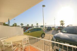 un balcón con una mesa y coches aparcados en un aparcamiento en Bord de mer, en Le Grau-du-Roi