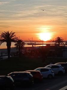 Una puesta de sol con coches aparcados en un estacionamiento. en Bord de mer, en Le Grau-du-Roi