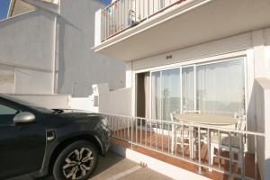 Un coche aparcado delante de un balcón con una mesa. en Bord de mer, en Le Grau-du-Roi