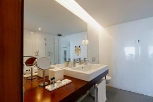 a bathroom with a large white sink and a mirror at Troia Design Hotel in Troia