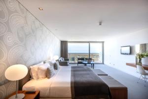 a bedroom with a large bed and a living room at Troia Design Hotel in Troia