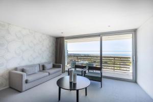 a living room with a couch and tables and a large window at Troia Design Hotel in Troia