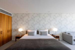 a bedroom with a bed with two lamps and a couch at Troia Design Hotel in Troia