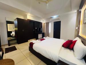 a bedroom with a large white bed with red pillows at Luxebay in Bangalore