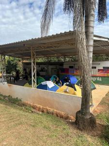 un gruppo di persone sedute sotto una tettoia con ombrelli di Camping Shangrilá São Thomé a São Thomé das Letras