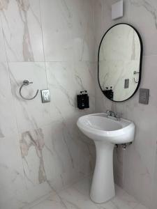 a white bathroom with a sink and a mirror at Suites Incoreli in Pachuca de Soto