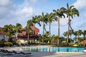a resort swimming pool with chairs and palm trees at Studio Papaye 24 in Sainte-Luce