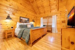 een slaapkamer met een bed in een blokhut bij Roudy’s Roost By Avada Properties in Pigeon Forge