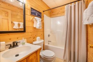 een badkamer met een wastafel, een toilet en een bad bij Roudy’s Roost By Avada Properties in Pigeon Forge +19 foto's