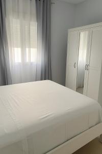 une chambre blanche avec un lit et une fenêtre dans l'établissement Alojamiento Baeza California 2B, à Baeza
