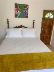 a bed with white sheets and a yellow blanket on it at Golden Nest in Port Antonio