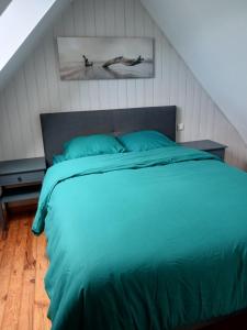 una camera da letto con un letto con un piumone verde di location vacance a Gommenecʼh