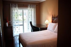 a bedroom with a bed and a desk and a window at Sunset Beach Apartment in Vila Praia de Âncora