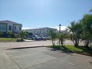 a parking lot with parked cars and palm trees at Nexus SUITE Airport HUB in Vila El Carmen