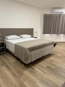 Un dormitorio con una cama grande y suelo de madera. en Hotel Acanto, en Rio Verde