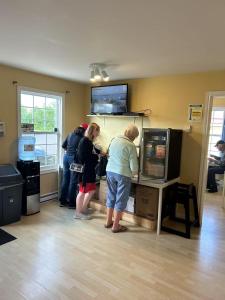 a group of people standing in a room playing a video game at The Cavendish Motel in Cavendish