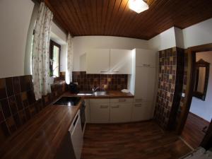 a kitchen with white cabinets and a wooden ceiling at Haus im Park in Sankt Kanzian