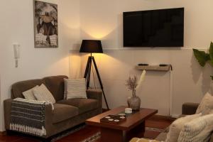 a living room with a couch and a tv on a wall at Casa Borda da Rocha in Nordeste