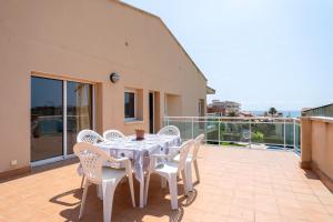 - Balcón con mesa blanca y sillas en Hauzify I Apartament Cala Pepo 2, en L'Ametlla de Mar