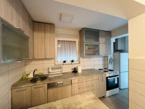 a kitchen with wooden cabinets and a sink and a stove at Apartman Park in Skopje