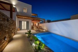 a villa with a swimming pool at night at Ios Art Suites in Ios Chora