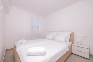 a white bedroom with a large bed with white sheets at Villa Mir Punta Radman in Petrcane