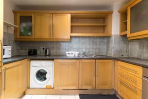 a kitchen with wooden cabinets and a washing machine at Spacious 2-Bed Apartment Opposite Santry Park & 10 Min Away from Airport in Dublin