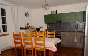 une cuisine avec des armoires vertes, une table et des chaises dans l'établissement Au Gré des Saisons - 3 chambres, à Gère-Belesten