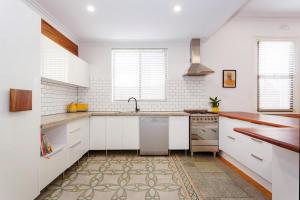 une cuisine avec des armoires blanches et un évier dans l'établissement Stone and Timber Heritage Retreat on South Terrace, à Fremantle