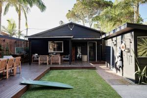 a house with a deck with a surfboard on it at The Black Ace Yamba in Yamba