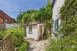 ein altes Backsteinhaus mit einer Tür im Hof in der Unterkunft Lorash Cottage, Ashbourne in Ashbourne