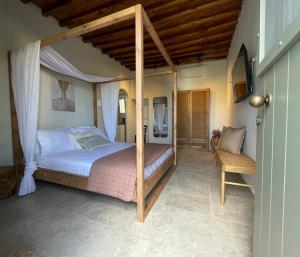 a bedroom with a canopy bed and a chair at Kisari Kimolos Cozy Studio in Kimolos