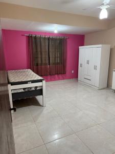 a room with a bed and a pink wall at Casa com Piscina em Itaipuaçu in Maricá