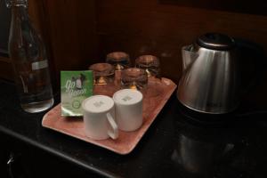 a tray with two mugs and glasses on a table at Nivaa Stays - Near JIPMER in Pondicherry +32 photos