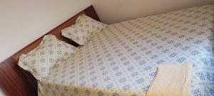 a bed with blue and white sheets and pillows at Résidence REHA, appart 2CH in Bafoussam