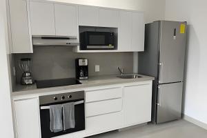 a kitchen with white cabinets and a stainless steel refrigerator at Costa Paraíso D-10 Estudio in Bucerías